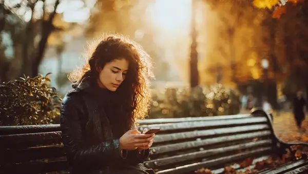 Cimientos, de Adri Kastel: lo vi tantas veces que tuve que pararme a entenderlo Persona sentada en un banco en un parque otoñal mirando el móvil, imagen ambiental para introducir el análisis de la formación Cimientos